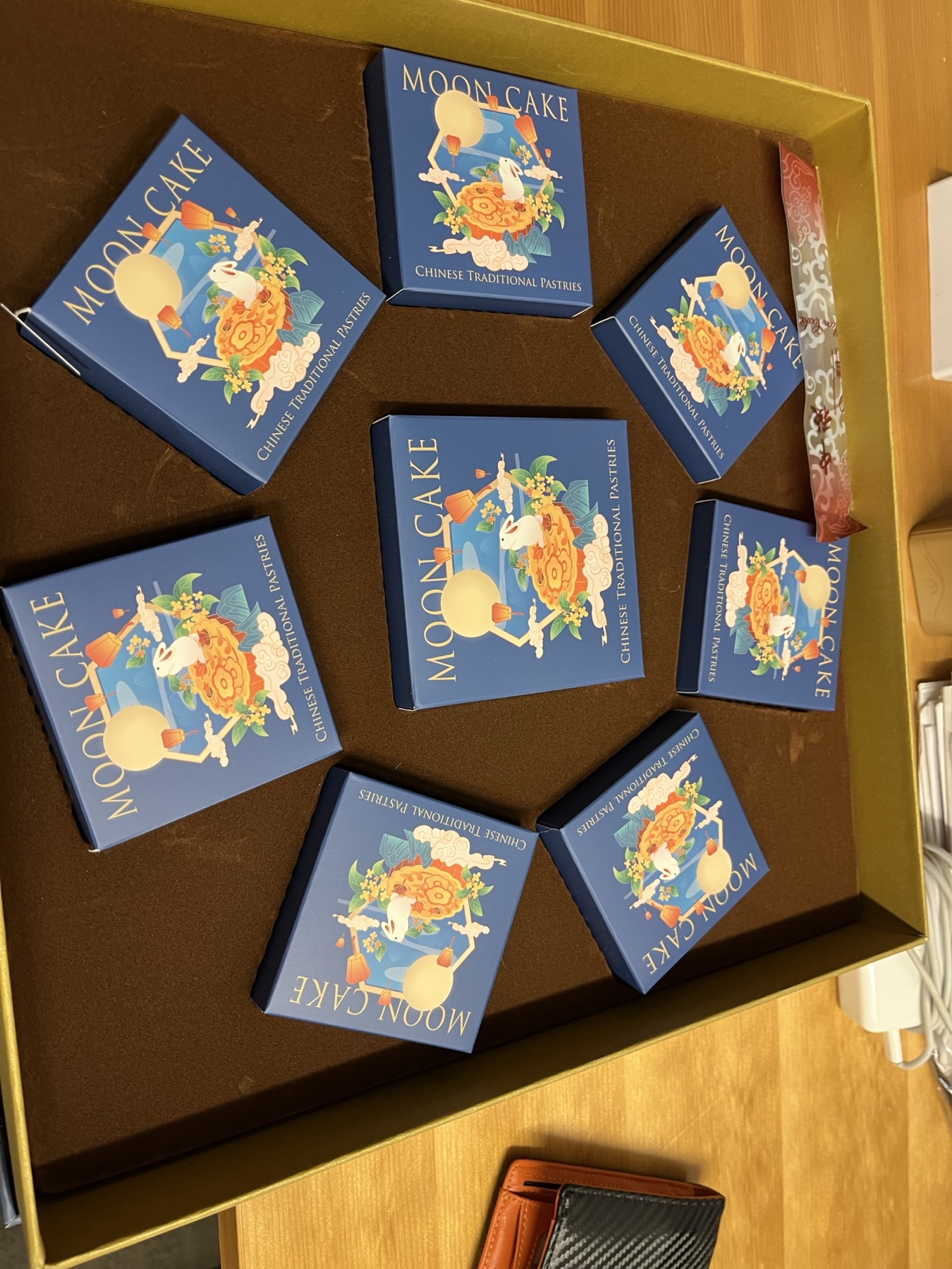Nine small blue boxes labelled Moon Cake, decorated with a rabbit and a full moon, arranged in a circle inside a brown gift box.